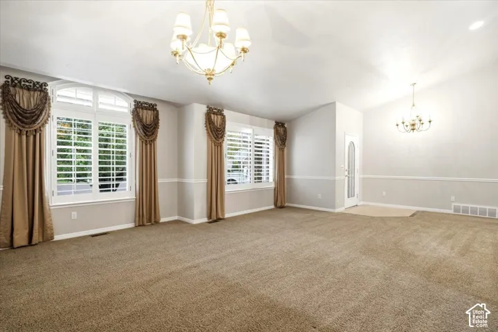 Vaulted ceilings, arch-top windows with plantation shutters, decorative drapery, and two chandeliers