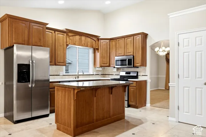 Kitchen with wood-finish cabinetry, stainless steel appliances, and a central island with an integrated breakfast bar