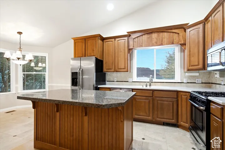 Kitchen featuring wood cabinetry, stainless steel appliances, a center island with a stone countertop, and tile flooring