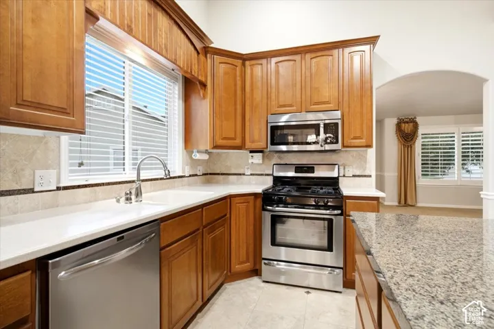 Kitchen featuring wood cabinetry, stainless steel appliances, white countertops, and a tiled backsplash