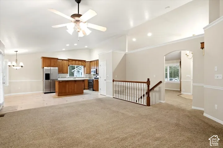 Vaulted ceilings with recessed lighting, integrated ceiling fan, wood cabinetry, stainless steel appliances, and a staircase with wood newel posts