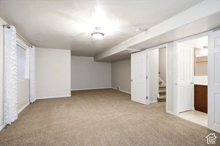 Carpeted open-concept room with neutral wall tones, a semi-flush mount ceiling light, and built-in doors