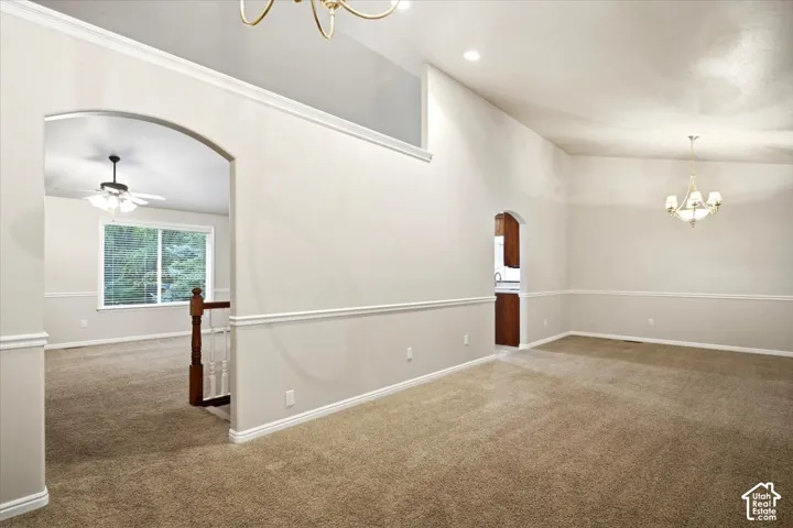 Vaulted ceiling, arched doorways, chair rail molding, recessed lighting, and a chandelier