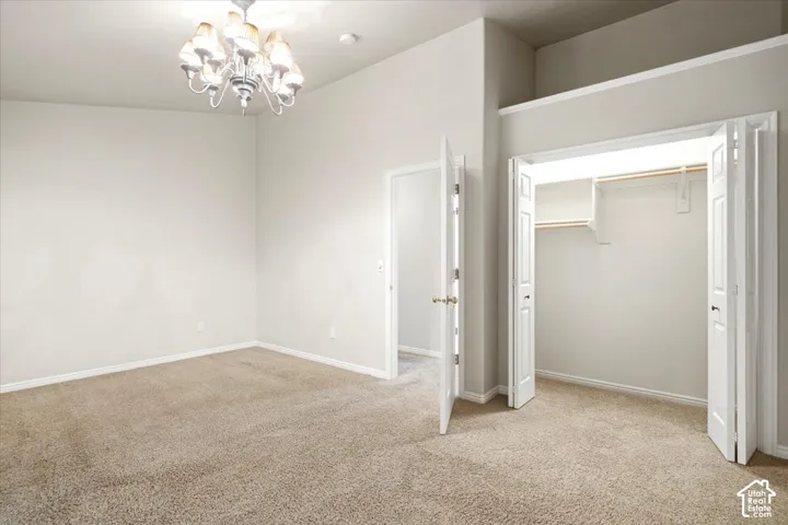 Carpeted room with a chandelier, bi-fold closet doors, and interior doors