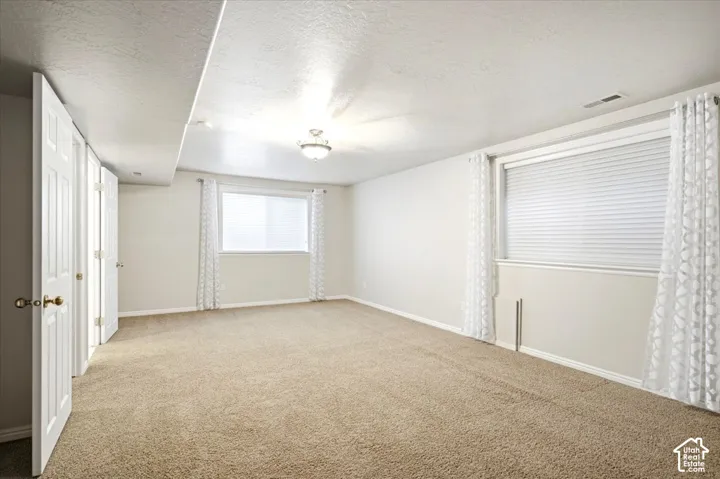 Carpeted room featuring multiple windows with blinds, bi-fold closet doors, and recessed ceiling lighting