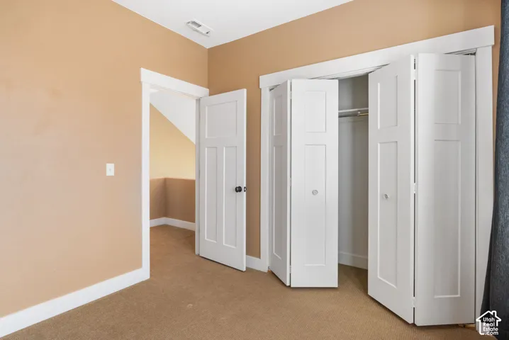 Warm-toned walls with white trim, bi-fold closet doors, and carpet flooring