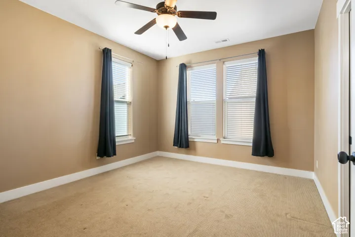 Recessed lighting, ceiling fan with integrated lighting, three windows with blinds, and light-colored carpeting