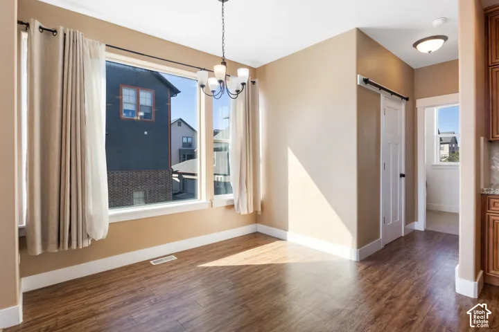Expansive window, wood-finish flooring, ceiling-mounted light fixture, warm-toned walls, and a barn door