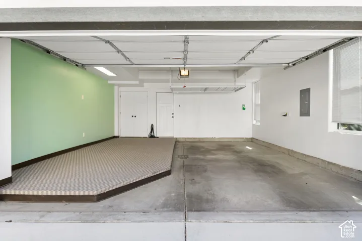 Concrete flooring, built-in shelving, two windows with blinds, recessed lighting, and a raised carpeted platform