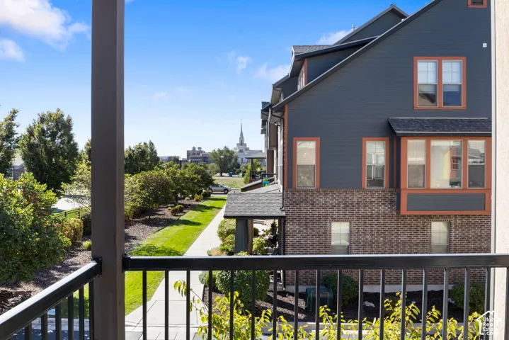 Black metal balcony railing overlooking a manicured lawn and a multi-story building featuring brick and siding