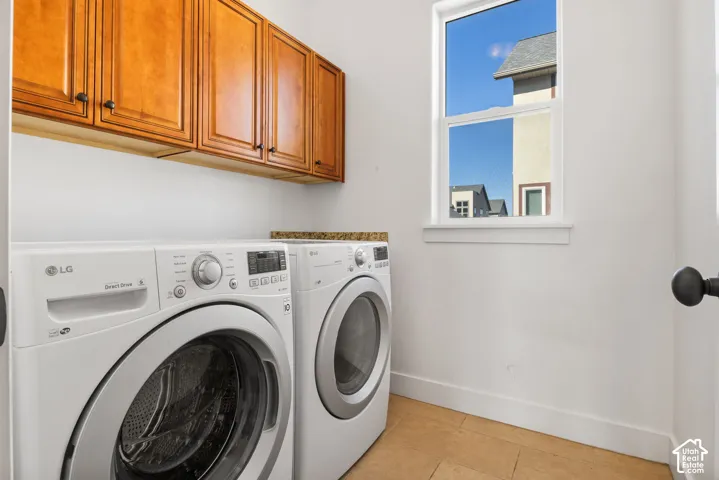 Wood-finish cabinetry with dark hardware, a single window, and light-toned tile flooring