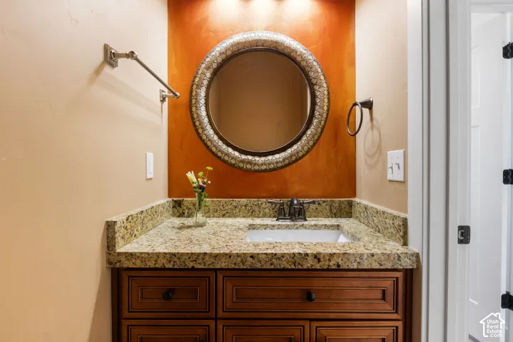 Bathroom vanity with a granite countertop, integrated sink, and wood-finish cabinetry