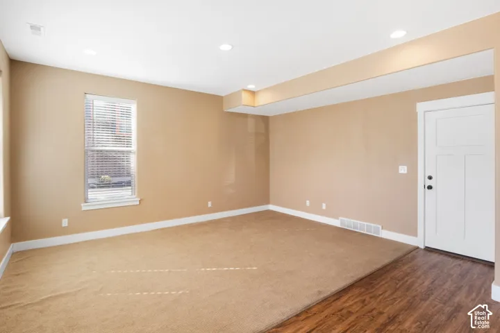 Recessed lighting, baseboard trim, carpet flooring, wood-finish flooring, and a paneled door