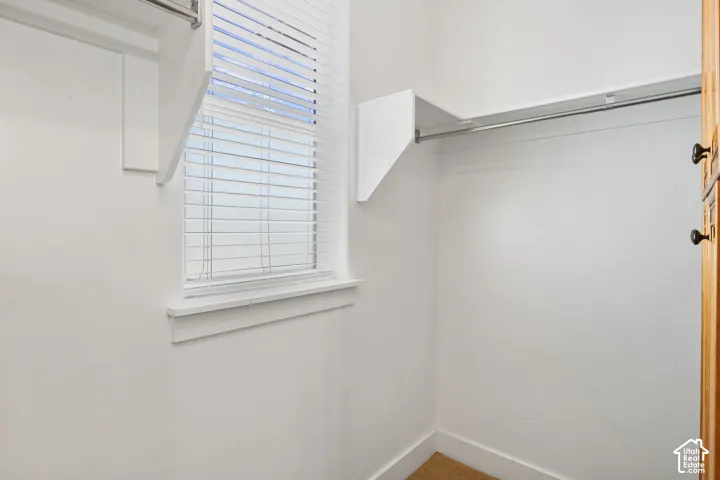 Built-in shelving and hanging rod with a window featuring horizontal blinds