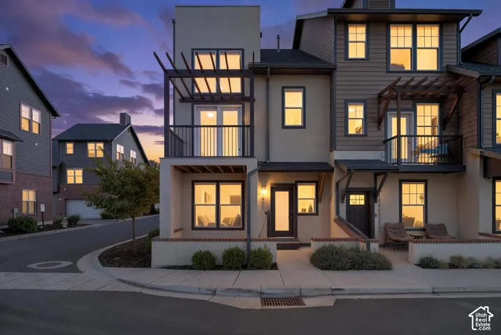 Multi-story residence featuring a mixed-material facade, private balcony with metal railing, and a ground-level patio area