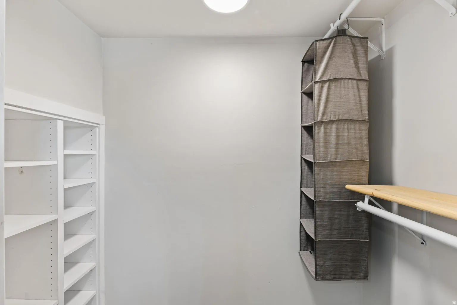 Built-in shelving with adjustable shelves, wood-finish closet rod, and overhead lighting