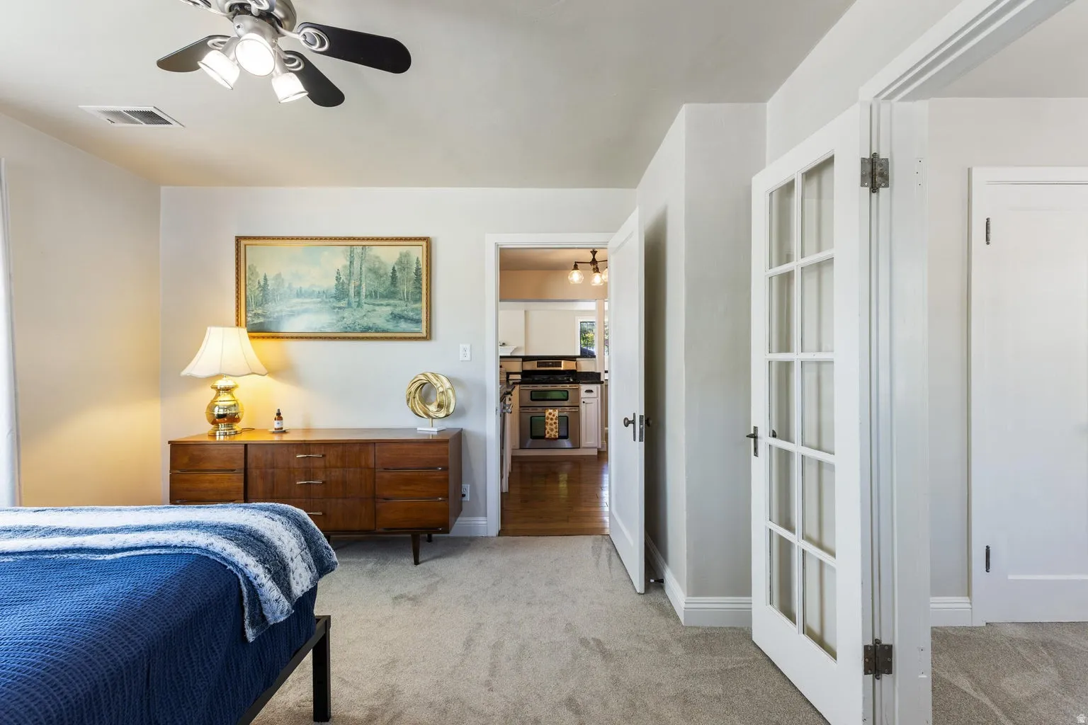 Recessed lighting, wood-finish flooring, and white cabinetry visible through the doorway