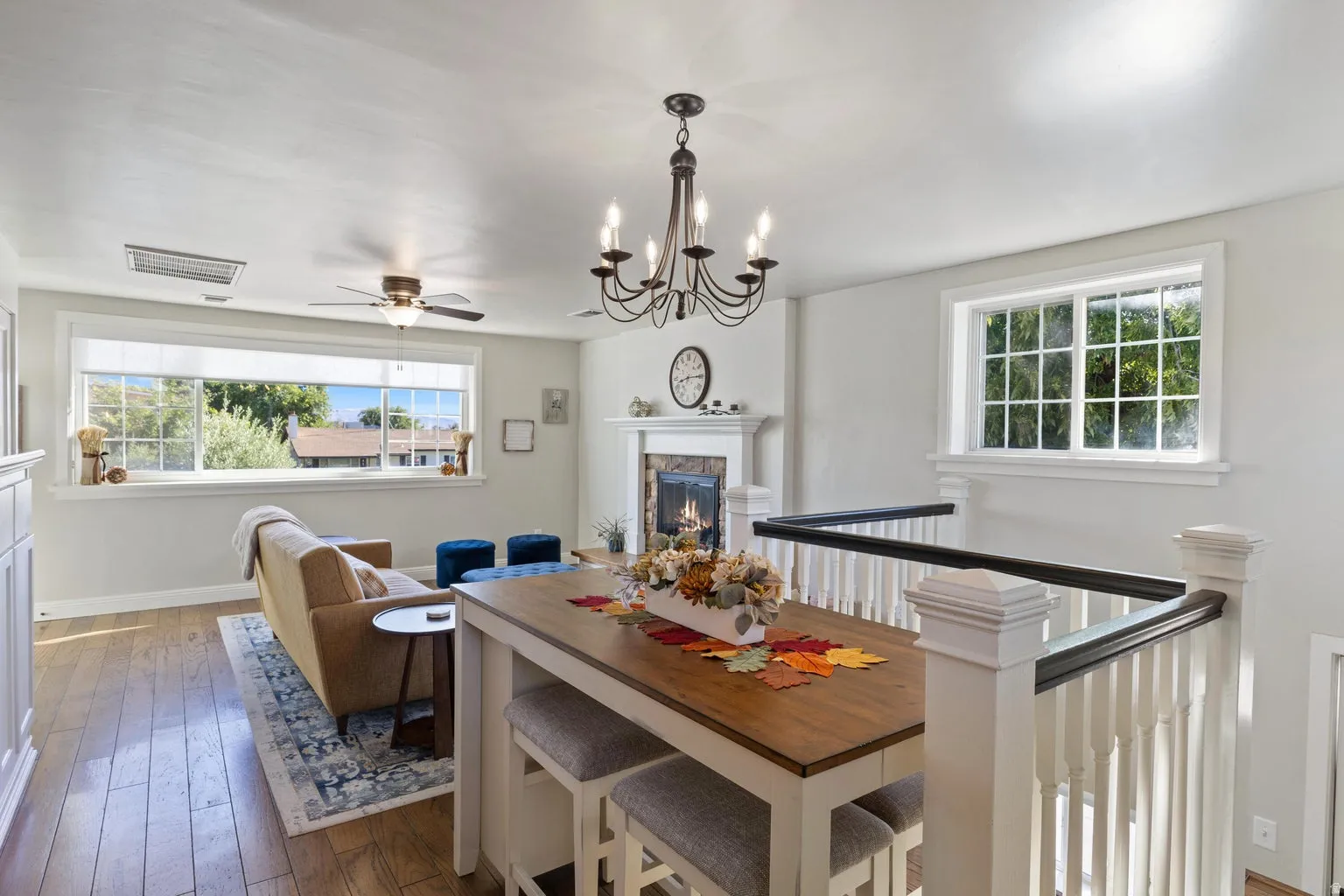 Warm living area featuring wood-finish flooring, a fireplace with a white mantel, and a multi-paned window
