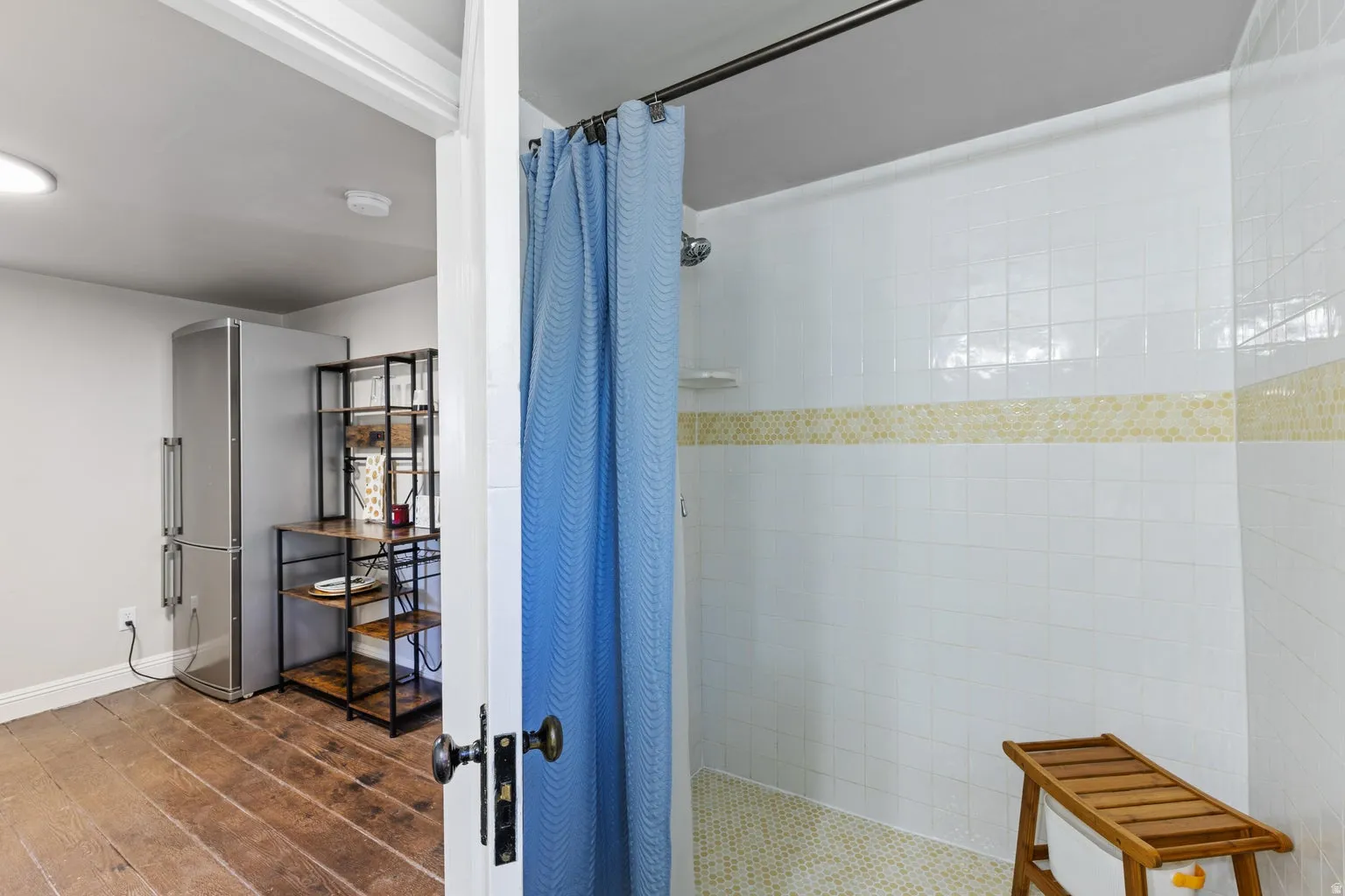 White tiled shower with a patterned accent band and a tiled floor