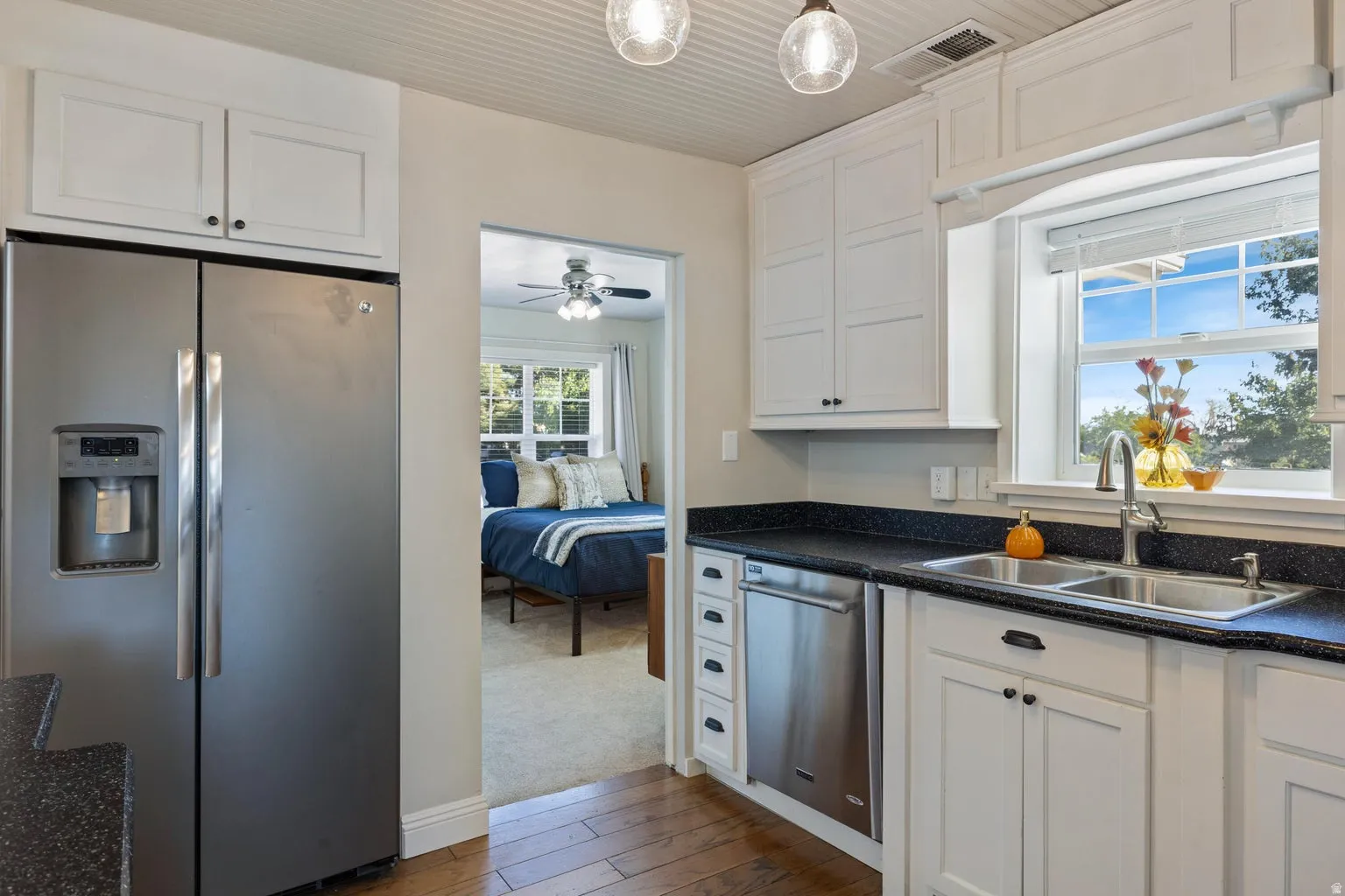 Kitchen featuring white cabinetry, dark speckled countertops, a stainless steel side-by-side refrigerator, and a double basin sink