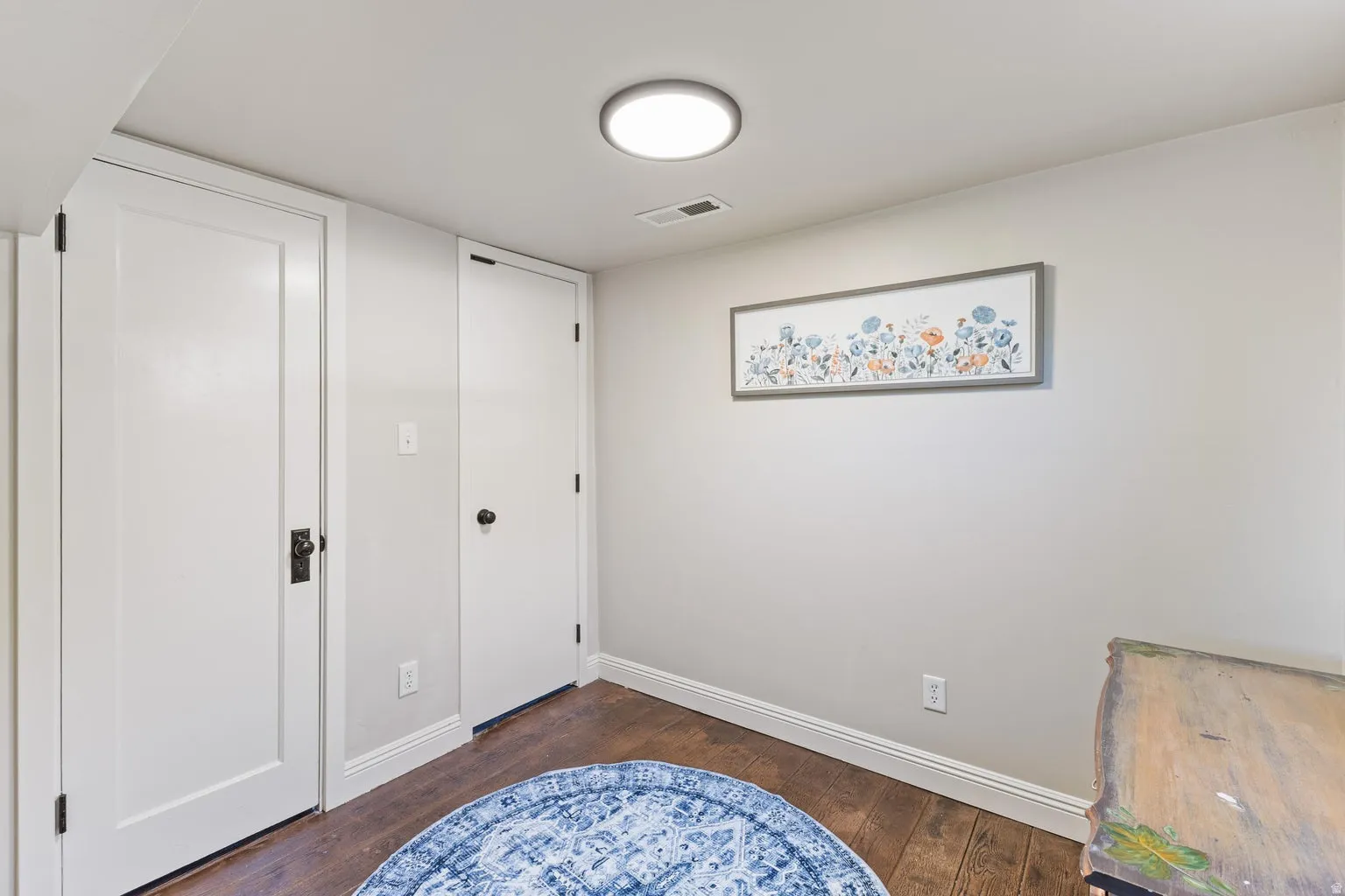 Wood-finish flooring, white trim, recessed lighting, and two panel doors