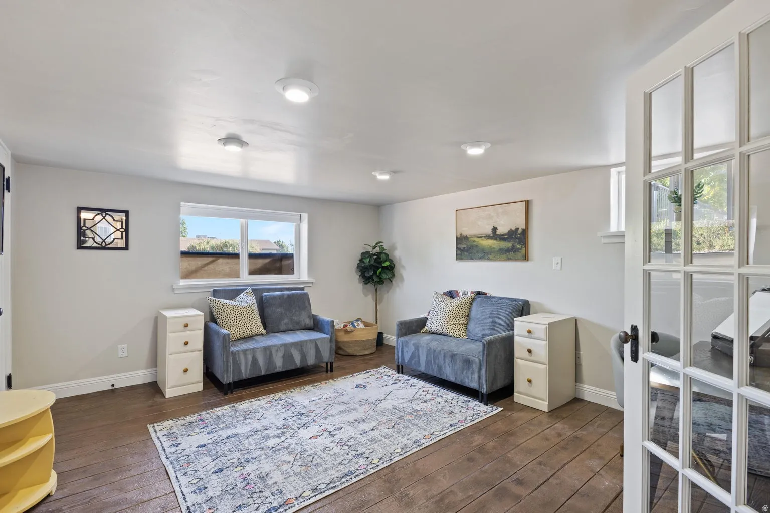 Wood-finish flooring with white baseboards, recessed lighting, and a white framed window