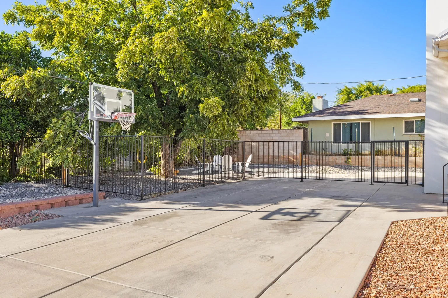 Expansive concrete pad, metal fencing, and a built-in basketball hoop