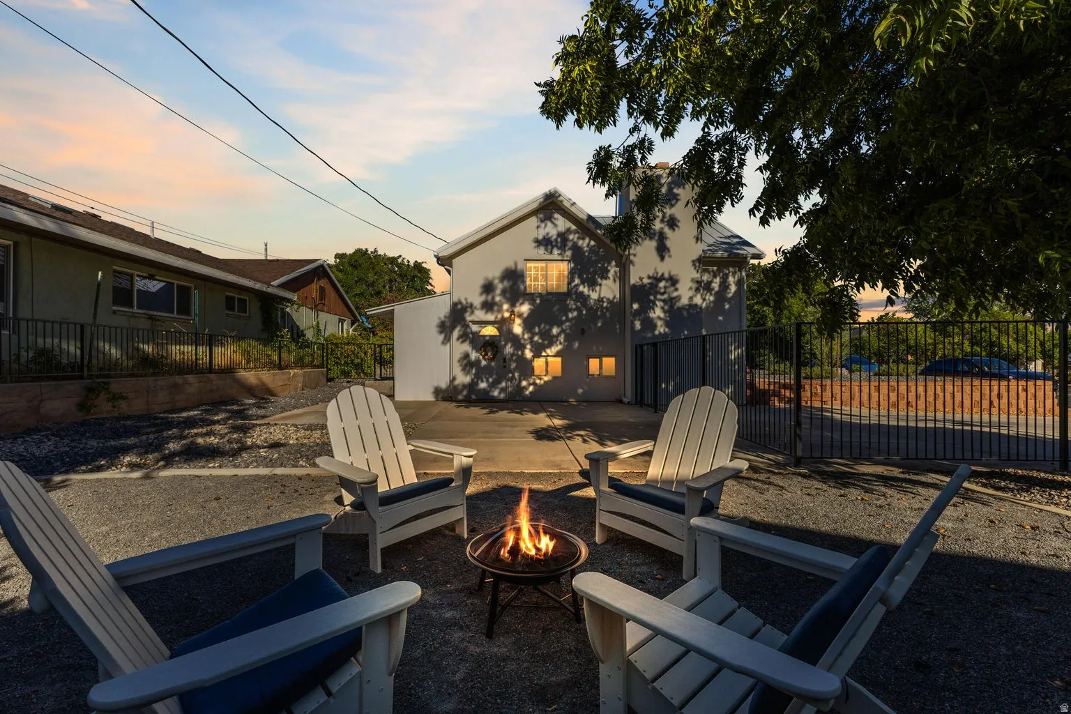 Outdoor fire pit area with gravel hardscaping and a black metal fence