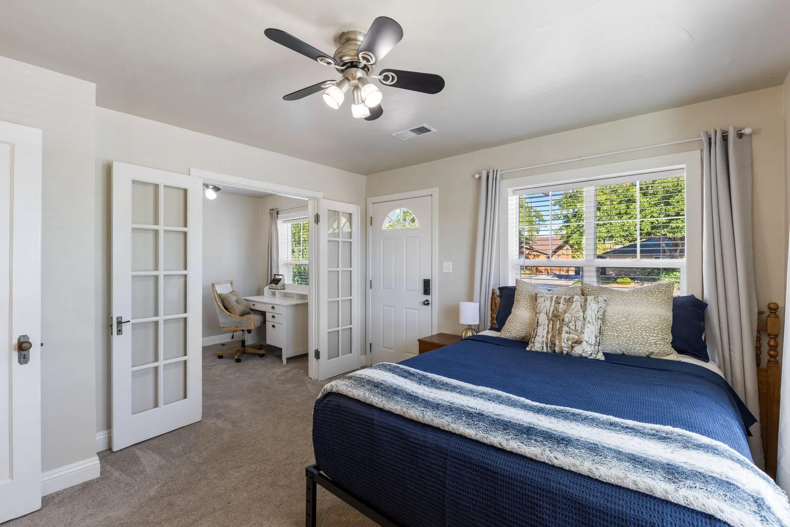 Ceiling fan, window with blinds, French doors, carpet flooring, and a white door with hardware