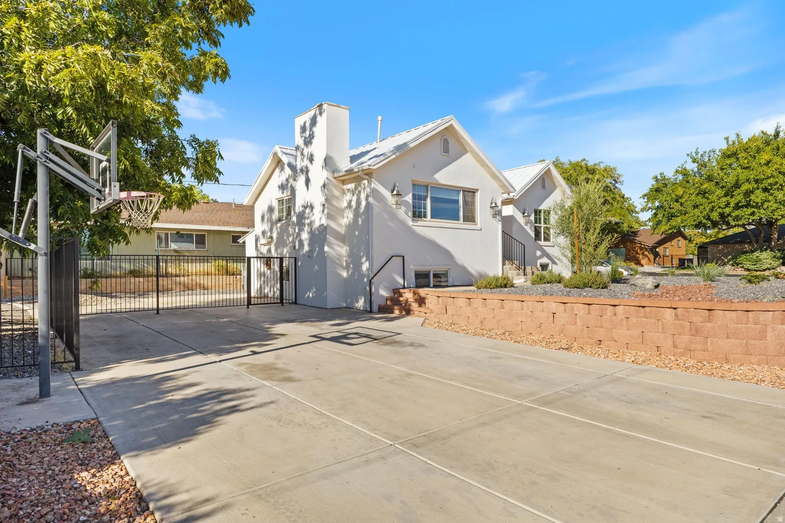 Concrete paved area with painted lines, black metal fencing, and a red brick retaining wall