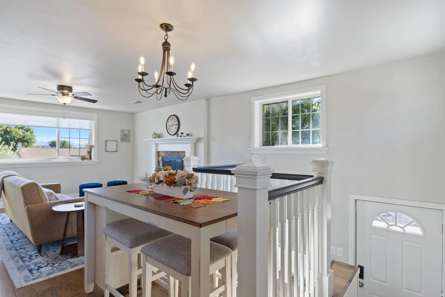 Open-concept living space featuring wood-finish flooring, a white mantel, and a ceiling fan