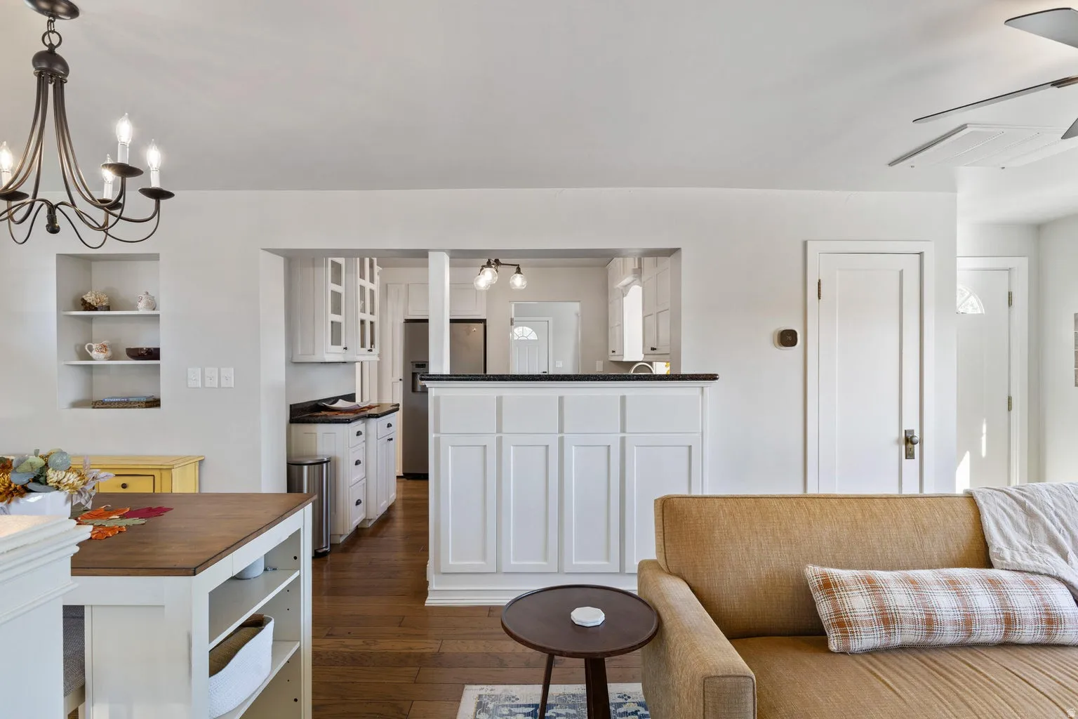 Hardwood flooring, white cabinetry, built-in shelving, dark countertops, and a modern ceiling fan