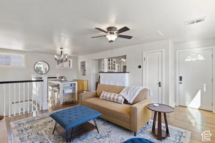Bright living area featuring wood-finish flooring, a ceiling fan with integrated lighting, and a white paneled door with an arched transom