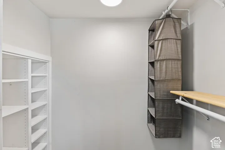 Built-in shelving with adjustable shelves, wood-finish closet rod, and overhead lighting