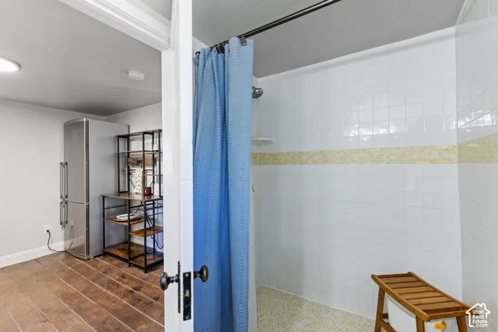 White tiled shower with a patterned accent band and a tiled floor