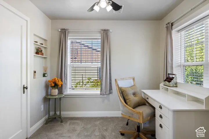 Built-in shelving, window with blinds and drapes, ceiling fan, and light-toned wall paint