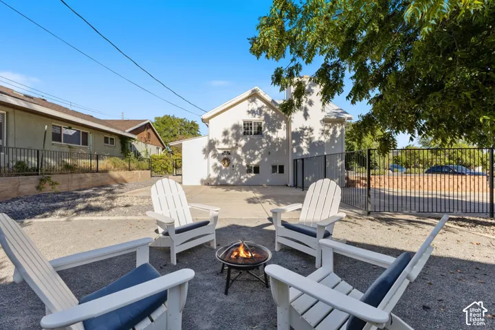 Rear exterior with a concrete patio, white stucco finish, and wrought iron fencing