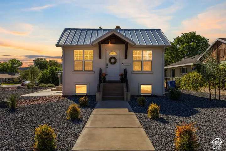 Stucco exterior with a metal roof, concrete walkway, and gravel landscaping