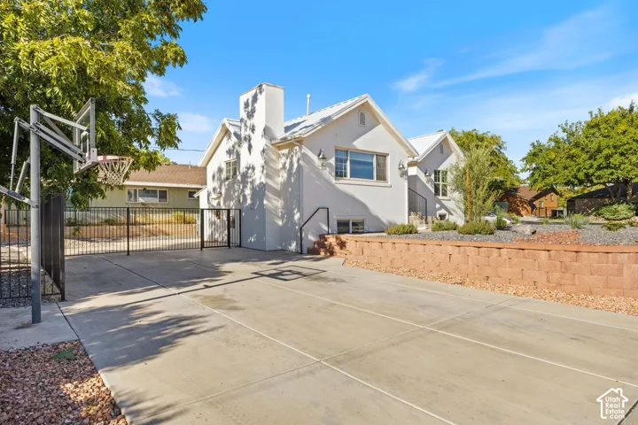 Concrete paved area with painted lines, black metal fencing, and a red brick retaining wall