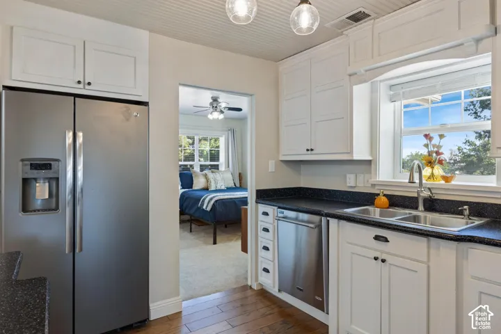 Kitchen featuring white cabinetry, dark speckled countertops, a stainless steel side-by-side refrigerator, and a double basin sink