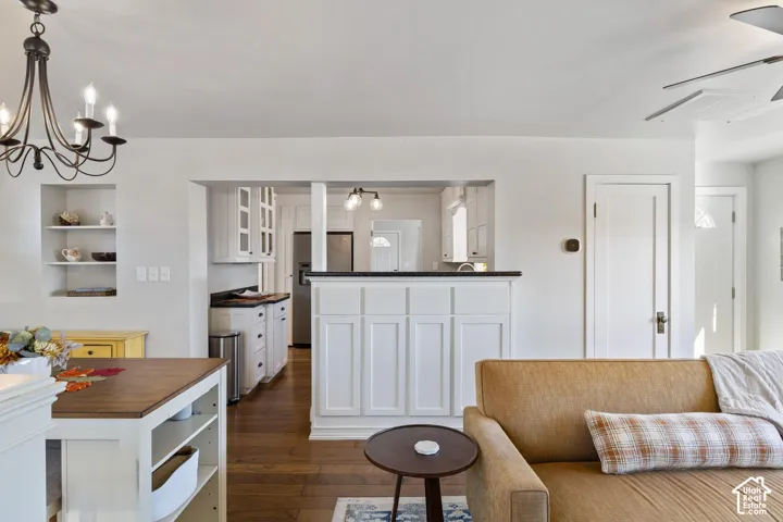 Hardwood flooring, white cabinetry, built-in shelving, dark countertops, and a modern ceiling fan