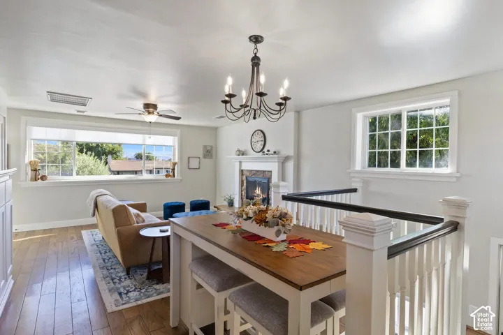 Warm living area featuring wood-finish flooring, a fireplace with a white mantel, and a multi-paned window