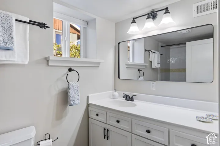 White shaker-style vanity with dark hardware, a single basin sink, and a spacious countertop