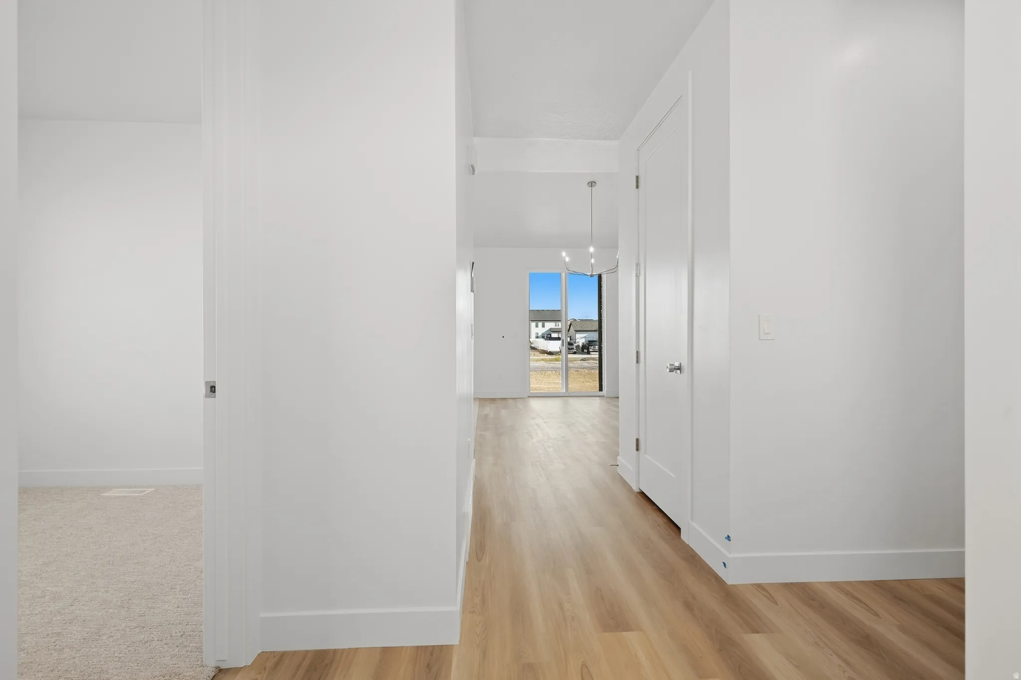 Wood-finish flooring, white walls, and a contemporary pendant light fixture