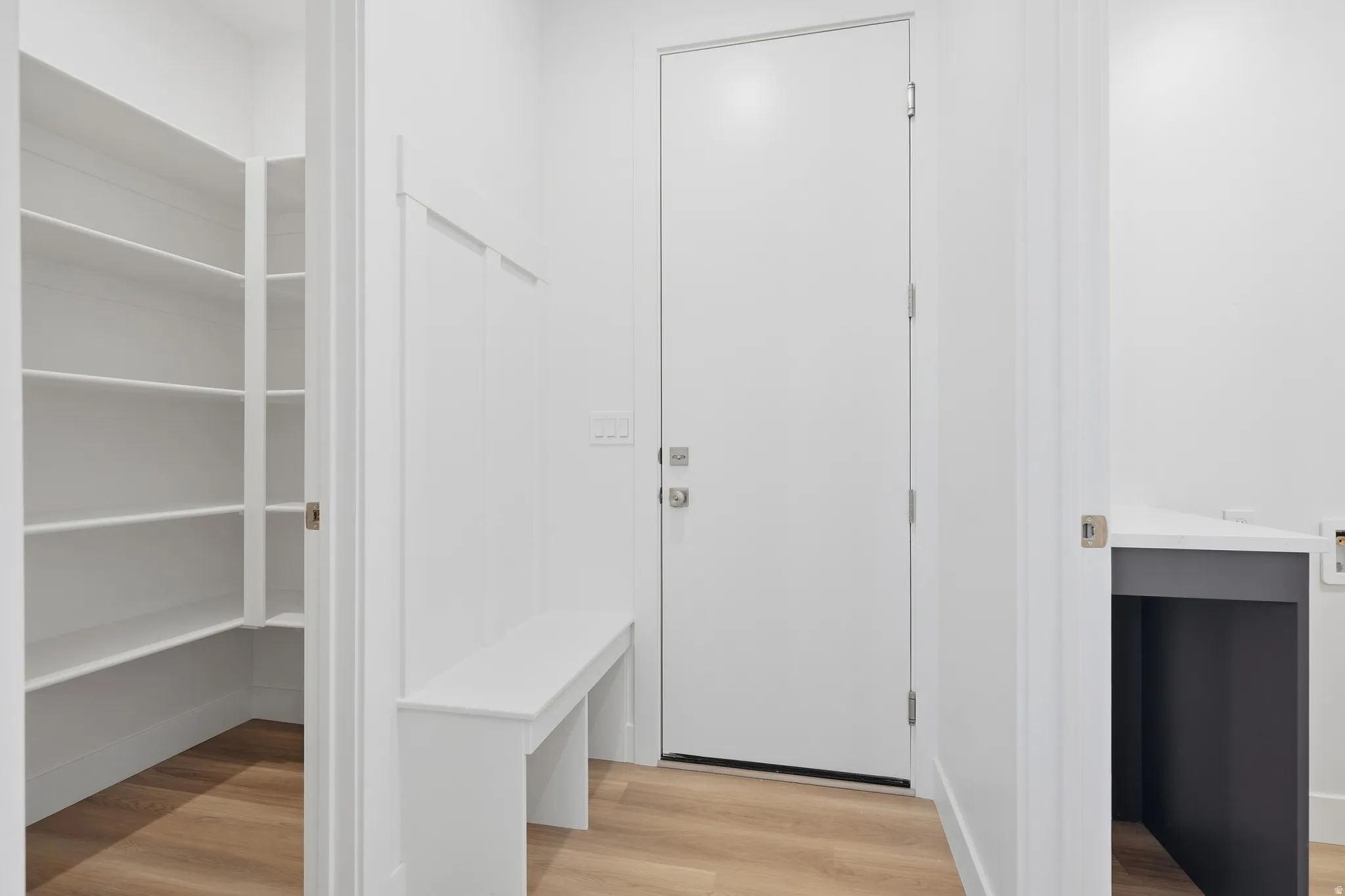 Built-in pantry with ample shelving, wood-finish flooring, built-in bench, and a built-in desk area