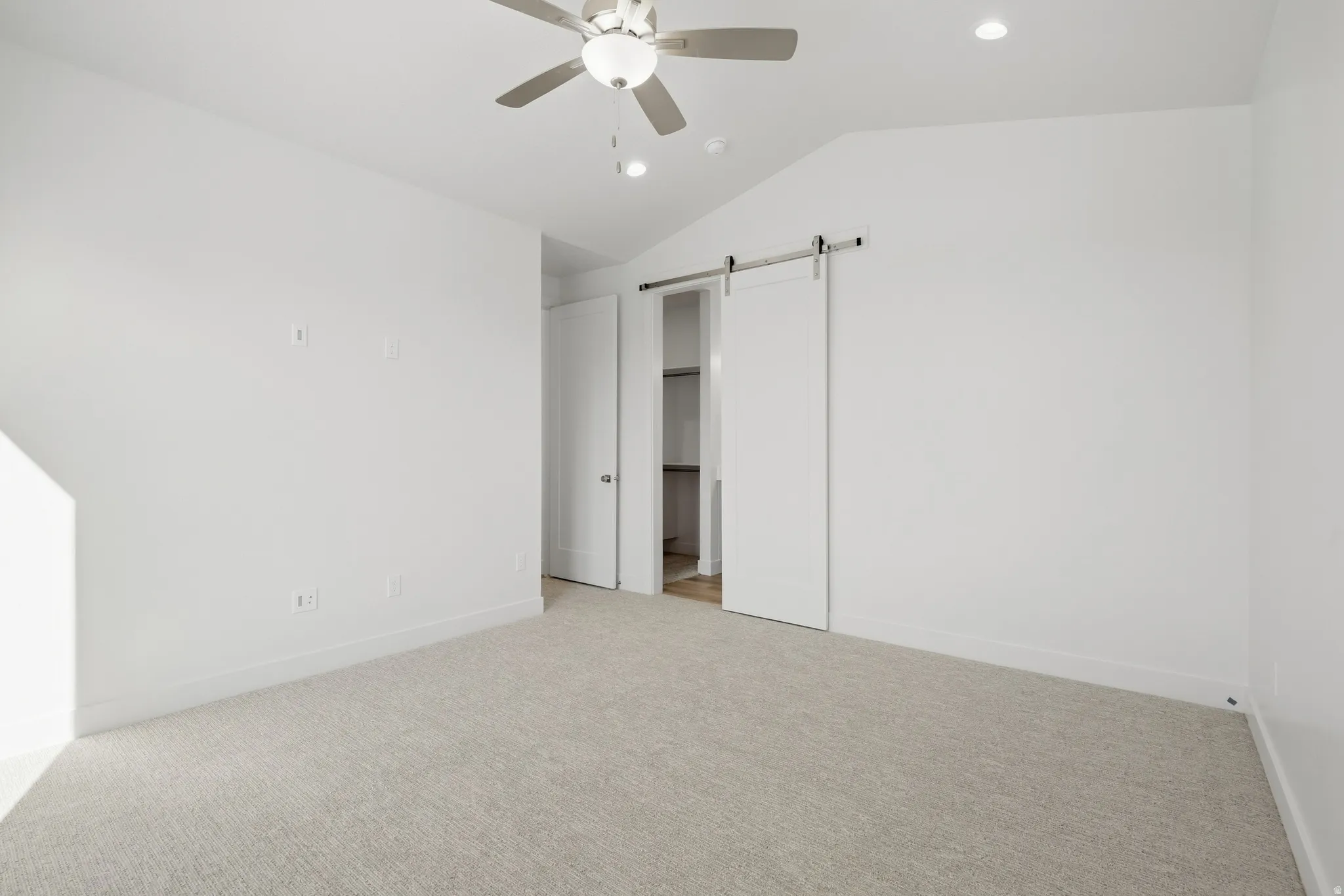 Vaulted ceiling, carpeted flooring, ceiling fan, recessed lighting, barn door entry