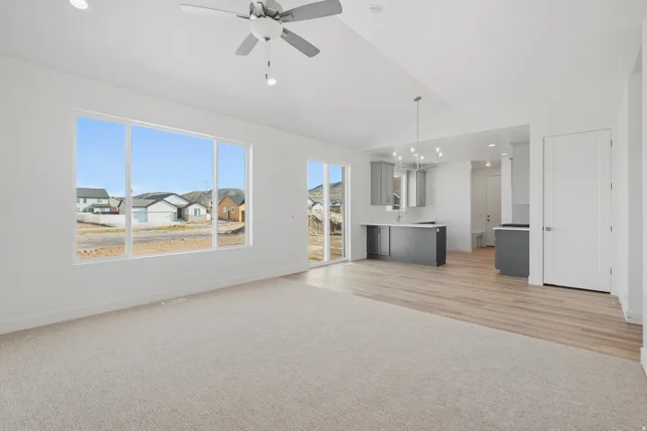 Carpeted living area with a large window, recessed lighting, and a ceiling fan