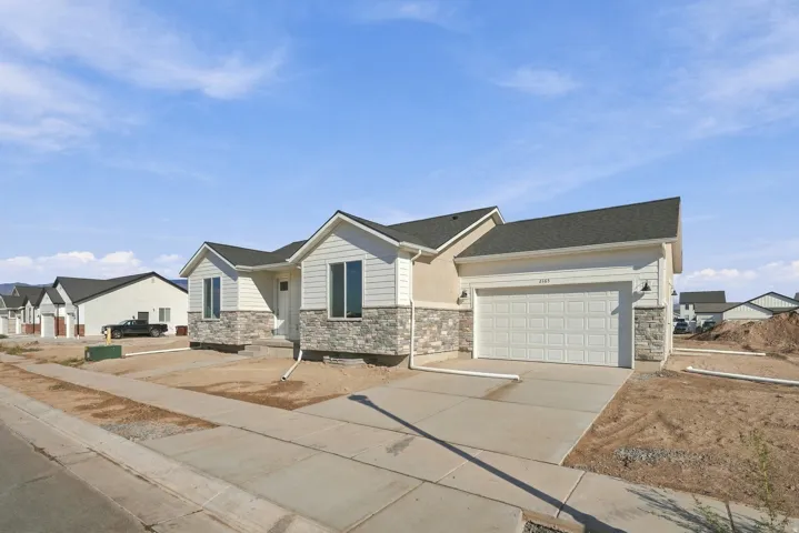Contemporary ranch-style exterior featuring a two-car garage, stone veneer accents, horizontal siding, and a concrete driveway