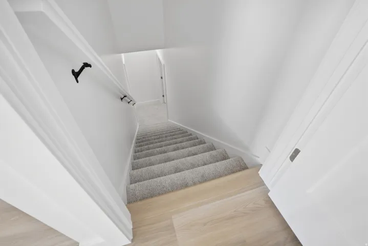 Carpeted staircase with light wood-finish flooring at the landing