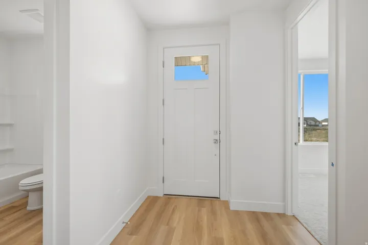 Entryway featuring wood-finish flooring, a white door with a clear glass insert, and crisp white walls